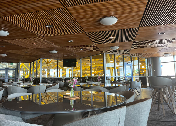 Several round tables and chairs in front of a wall of windows looking out onto the basketball arena