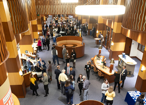 Dozens of people wearing name tags mill about the lobby of the Law library